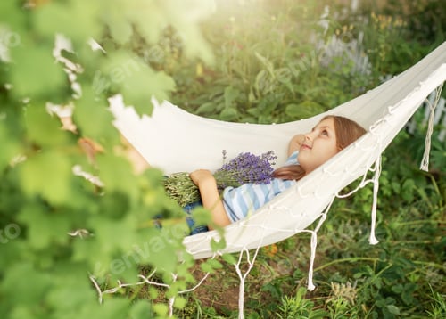 Preview: Girl Relaxing in Hammock Holding Purple Flowers