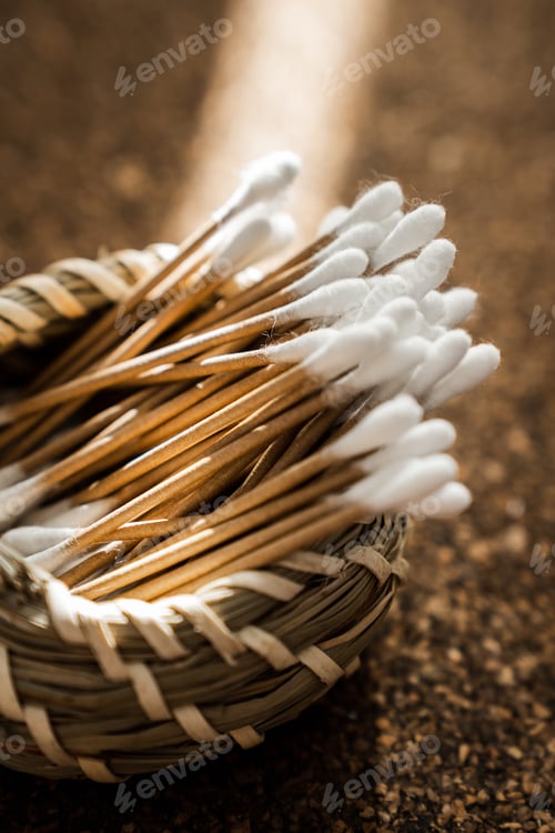 Preview: Wooden Cotton Swabs in Woven Basket on Cork Surface