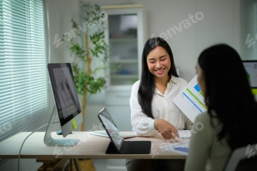 Preview: Asian businesswoman discussing financial data with colleague in office