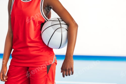 Preview: Female basketball player holding ball in gymnasium