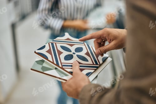 Preview: Close-up photo of a male seller holding some samples of ceramic tiles.