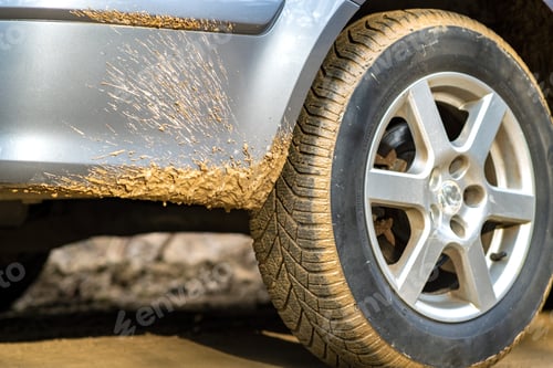 Preview: Close up of dirty car wheel with rubber tire covered with yellow mud