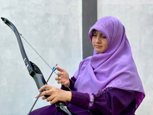 Preview: Hijab young woman sitting and preparing archery set