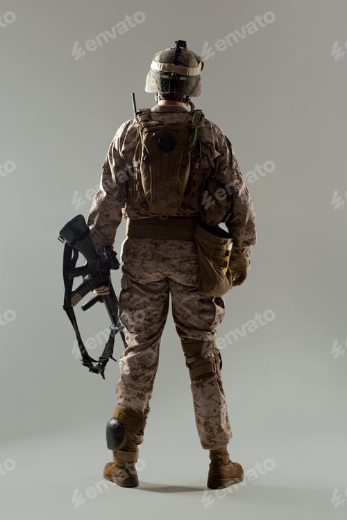 Preview: Soldier stands with weapon in plain background during training session indoors