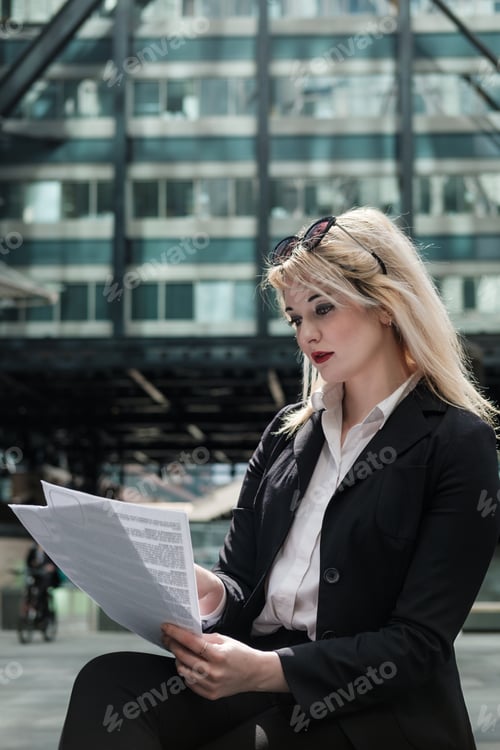Preview: Attractive young businesswoman working on some files outdoor.