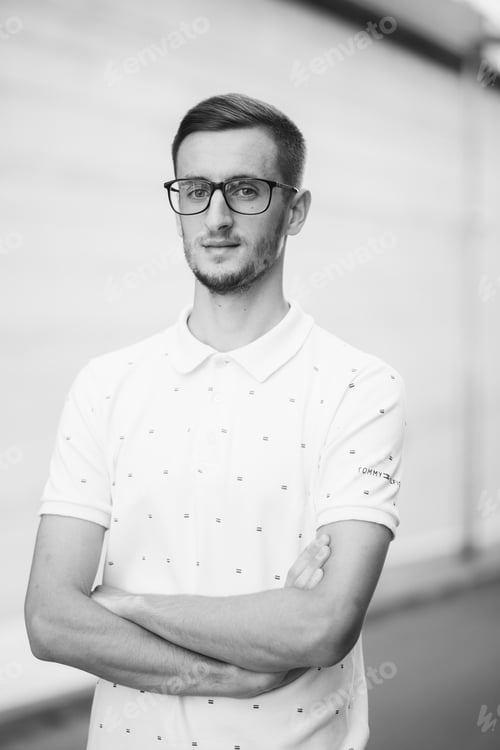Preview: Grayscale shot of a handsome guy in glasses with his hands crossed