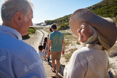 Preview: Three generation white family walking on a beach, grandparents in the foreground, over shoulder view