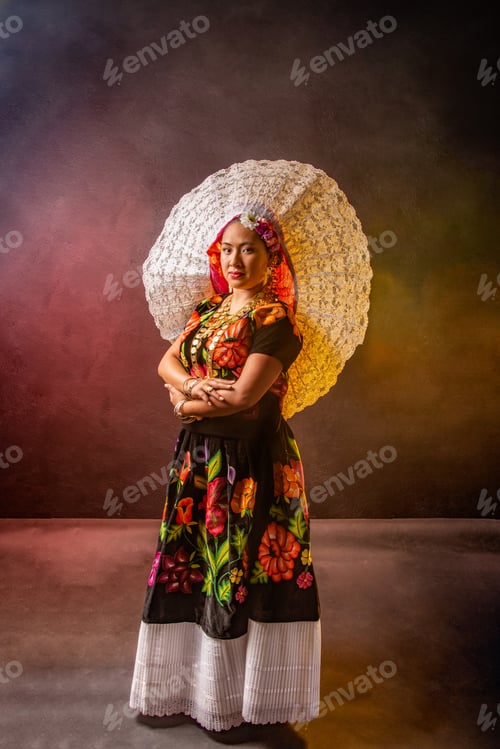 Preview: A woman wearing a flowery dress and a white hat stands in front of a wall