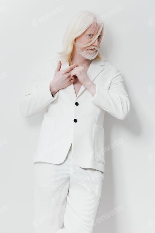Preview: Fashionable man in white attire posing against a minimalist white background, showcasing modern
