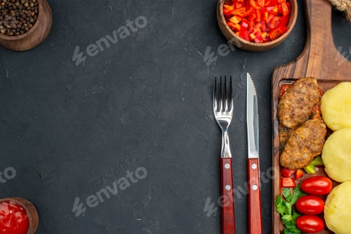 Preview: Top view of tasty cutlets chopped vegetables greens for dinner on dark background