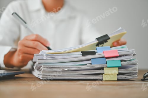 Preview: A person is writing on a stack of papers with a pen