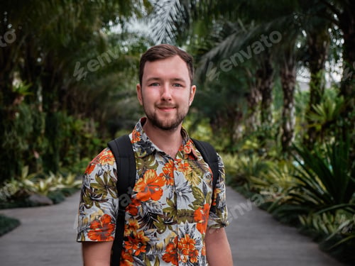 Preview: Caucasian man with a floral shirt posing with a walkway and palm trees in the background
