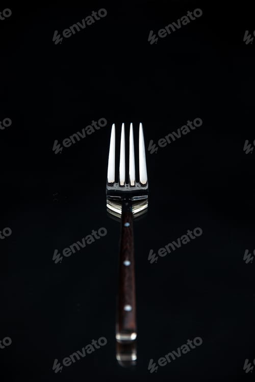 Preview: Close up shot of elegant shiny metal fork on black background with free space