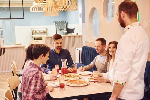 Preview: Chef delivers food. Group of young friends that sitting together indoors and eating pizza