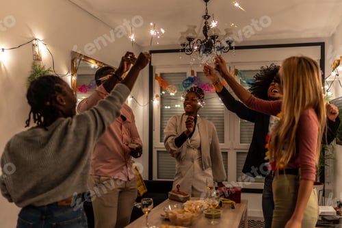 Preview: Multi-ethnic happy friends raising burning sparkler celebrating home party