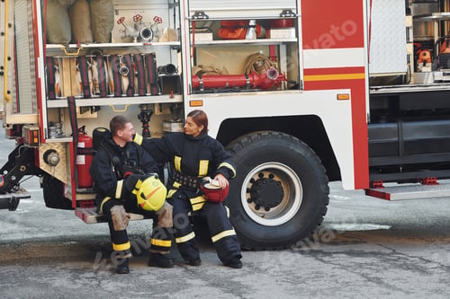 Preview: Male and female firefighters in protective uniform is outdoors together