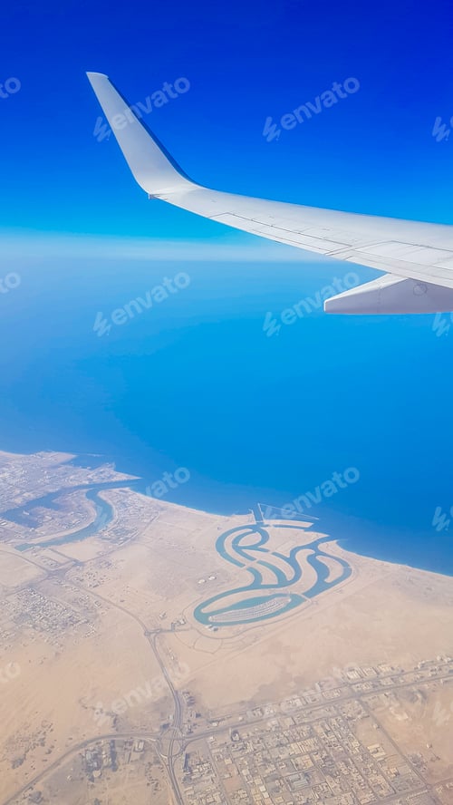 Preview: View from the window of plane on blue sky and earth with landscape of desert, sea and canals in
