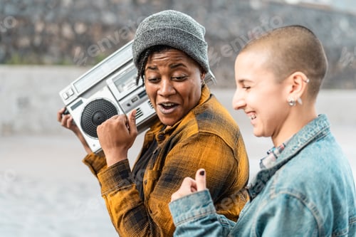 Preview: Happy multiracial women having fun dancing while listening to music with vintage boombox stereo