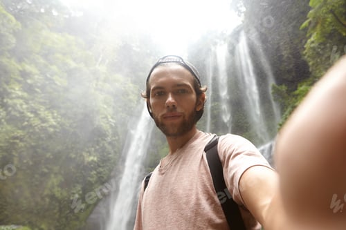 Preview: High-angle shot of handsome bearded male tourist taking selfie on front-facing camera of some electr