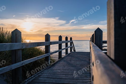 Preview: Wooden boardwalk pier stretches out into the sea at sunset