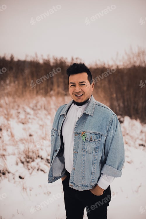 Preview: Hispanic brunette man with beard in denim jacket in winter in the middle of snow