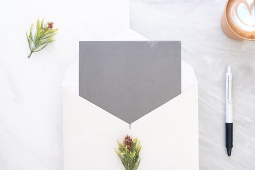 Preview: Top view of blank grey card in white envelop with pine leaf on two layer step of marble table