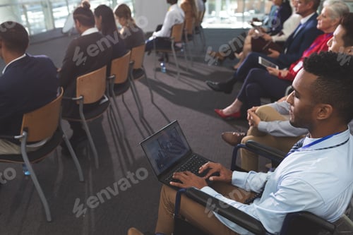 Preview: Young disabled African american businessman using laptop during seminar in office building