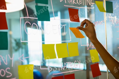 Preview: Hand of female executive sticking notes on glass board