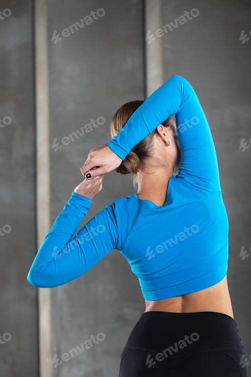 Preview: A young woman in sportswear makes a lock with her hands behind her back.
