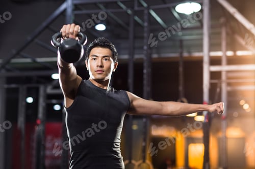 Preview: Young man training with kettlebell in crossfit gym