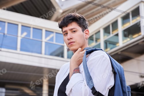 Preview: tattooed man in shirt with a backpack on his shoulder looking at the camera