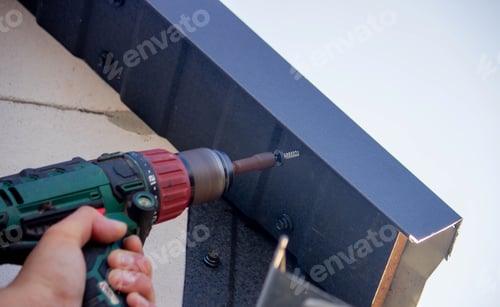 Preview: a man repairs the roof, tightens the self-tapping screw with a screwdriver