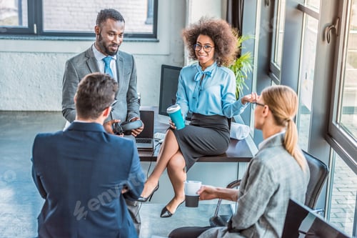 Preview: high angle view of multicultural businesspeople having coffee break in office