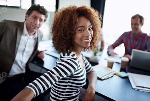 Preview: Portrait of an office worker sitting at a boardroom table with colleagues in the background