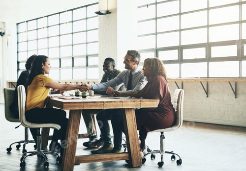 Preview: Shot of two business colleagues shaking hands over the boardroom table during a meeting