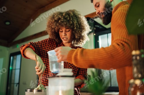 Preview: Couple preparing food with blender, adding water to mixture
