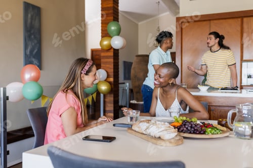 Preview: Friends enjoying conversation and snacks at home during casual gathering