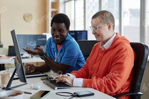 Preview: Two young intercultural colleagues discussing data on computer screen