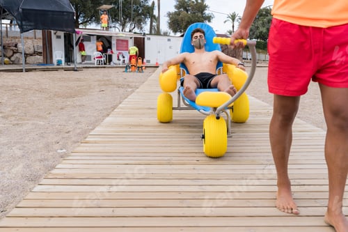 Preview: lifeguard dragging an injured man with chair on the beach