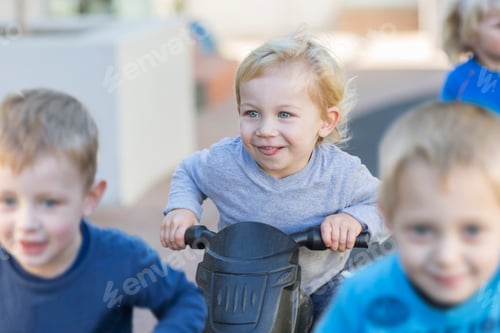 Preview: Boys at preschool racing push motorbikes in garden