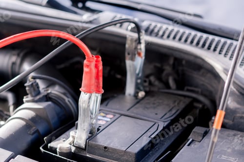 Preview: close-up At a service station a battery in a car with tongs connected for charging the battery