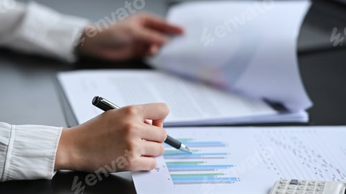 Vorschau: Nahaufnahme professionelle Geschäftsfrau, die einen Stift hält und Finanzdokumente analysiert.