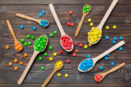 Preview: delicious colorful sweet candies on spoon on colored background .