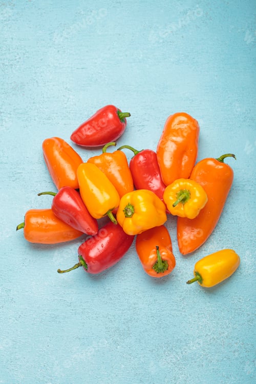 Preview: Sweet mini peppers lying on a blue tabletop