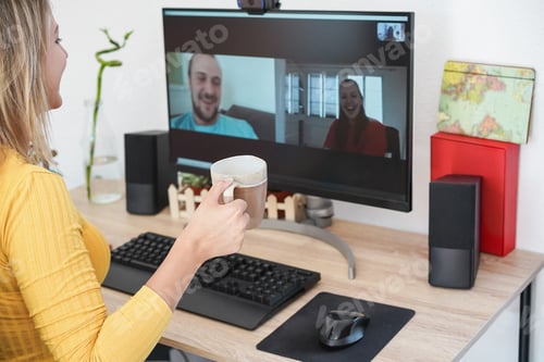 Preview: Young woman having an online video call with friends while drinking coffee at home - Focus on cup