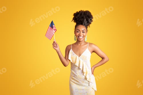Preview: Smiling millennial african american lady showing USA flag, isolated on yellow background