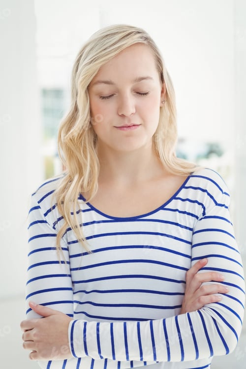 Preview: Adult woman standing wearing striped shirt and appearing calm in white room with blurred plants