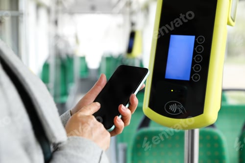 Preview: Woman with smartphone near contactless fare payment device in public transport, closeup