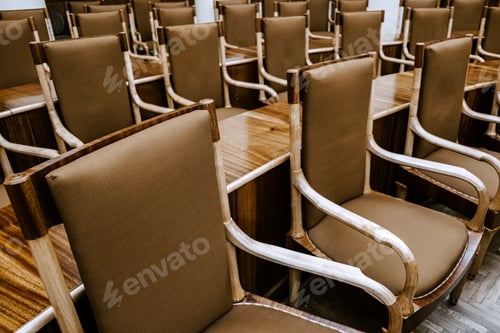 Preview: Rows of empty wooden chairs with fabric upholstery in a conference room, meeting or seminar setting