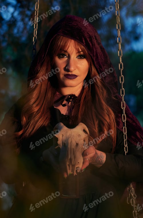 Preview: Woman disguised as a witch holding a skull in her hands
